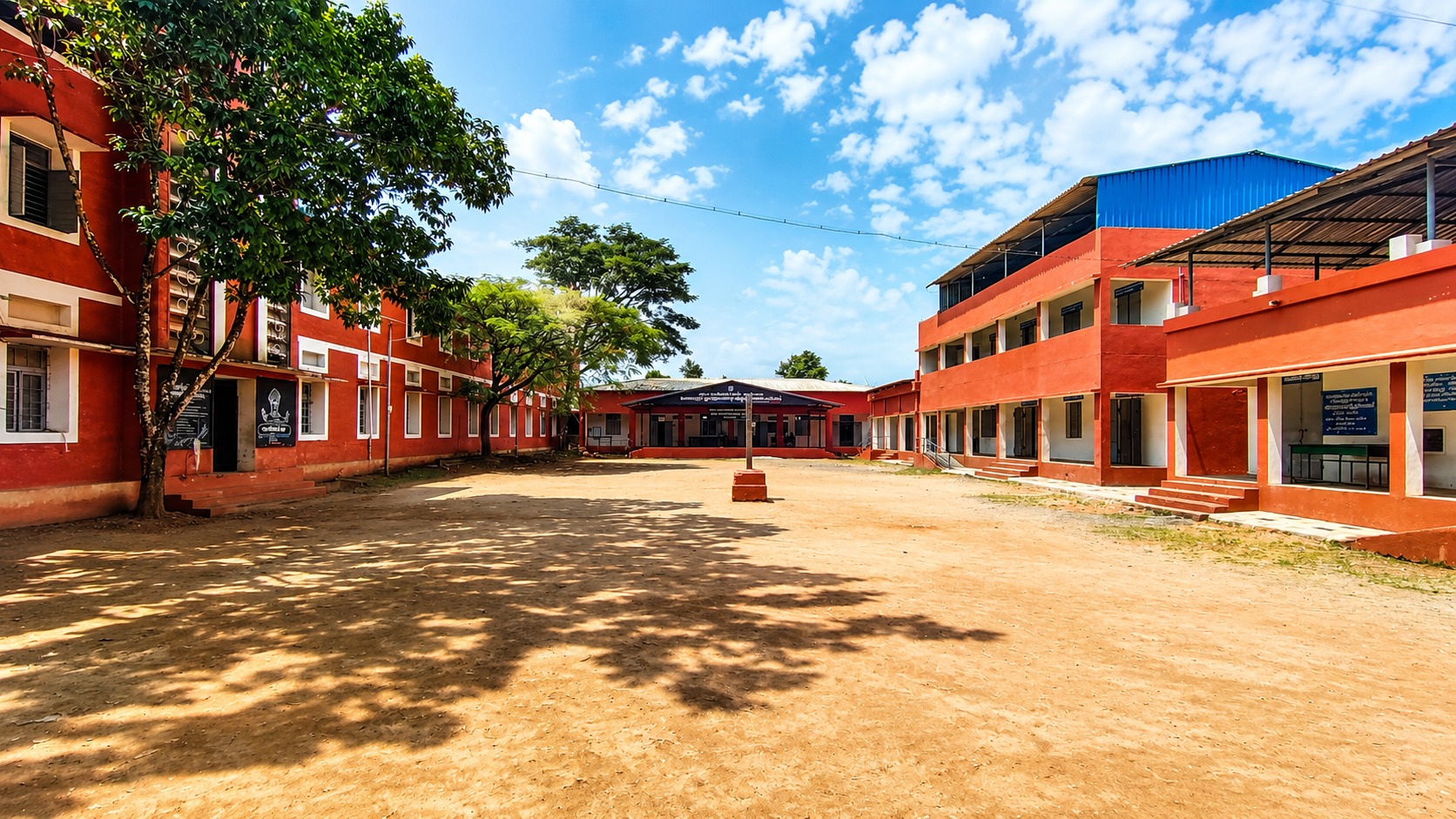 Campus courtyard — repainted classroom blocks under the new roofing