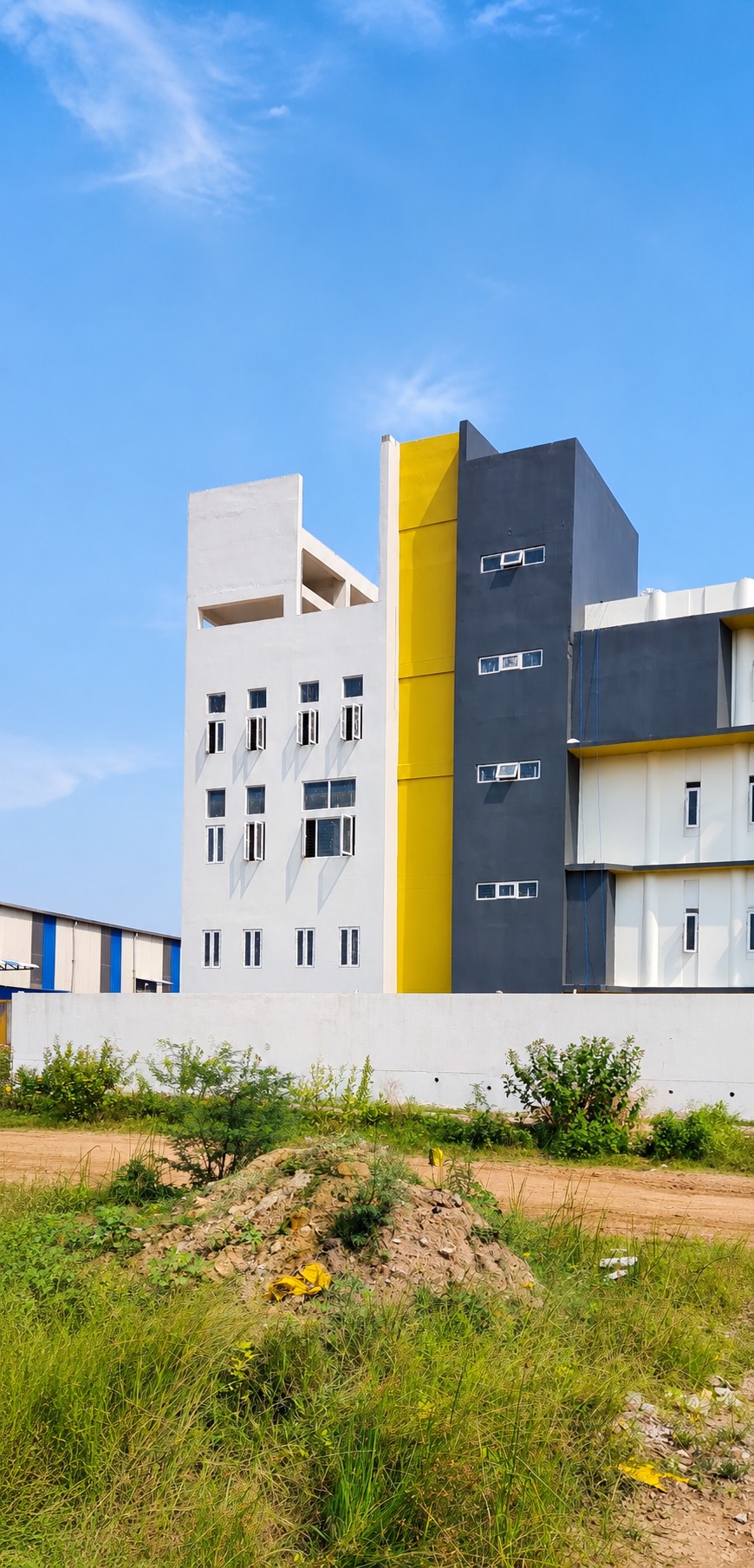 Exterior corner — the stair-tower's charcoal and yellow accent